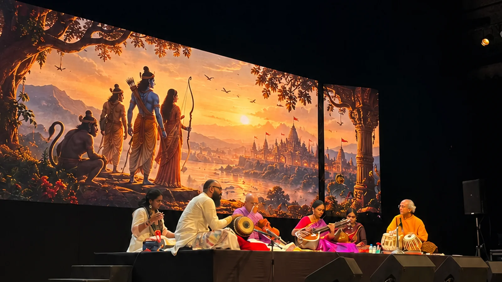 Musicians performing downstage while a wide LED backdrop shows Rāma, Sītā, Lakṣmaṇa and Hanumān looking out over Ayodhyā at sunrise